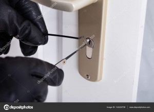 Close-up Of A Burglar With Gloves Picking Lock
